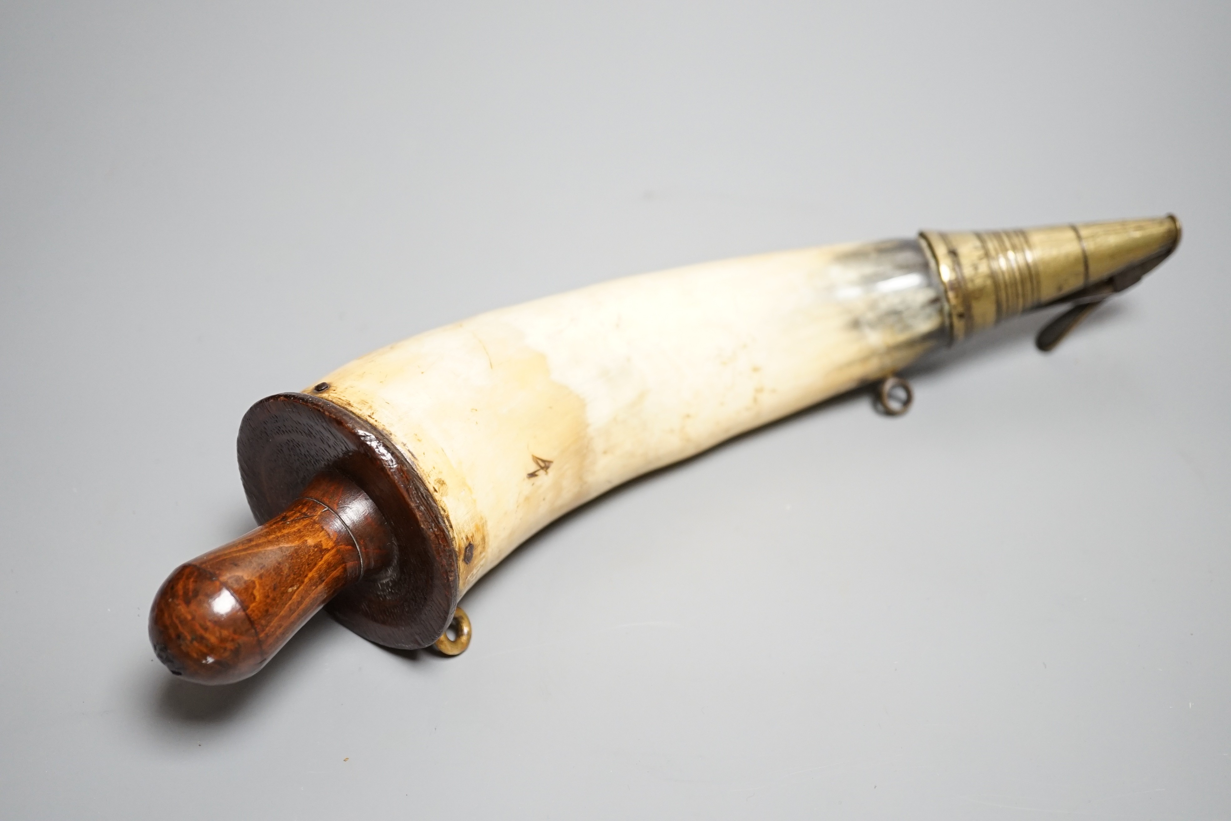 A British military Gunner's powder horn c.1800, cow horn body, sprung brass charger, wooden end cap and plug, two brass suspension rings, body branded with WD stamp and broad arrow. Length 29cms.